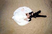 Beach wedding photo, bride and groom on the beach, laying on the sand,